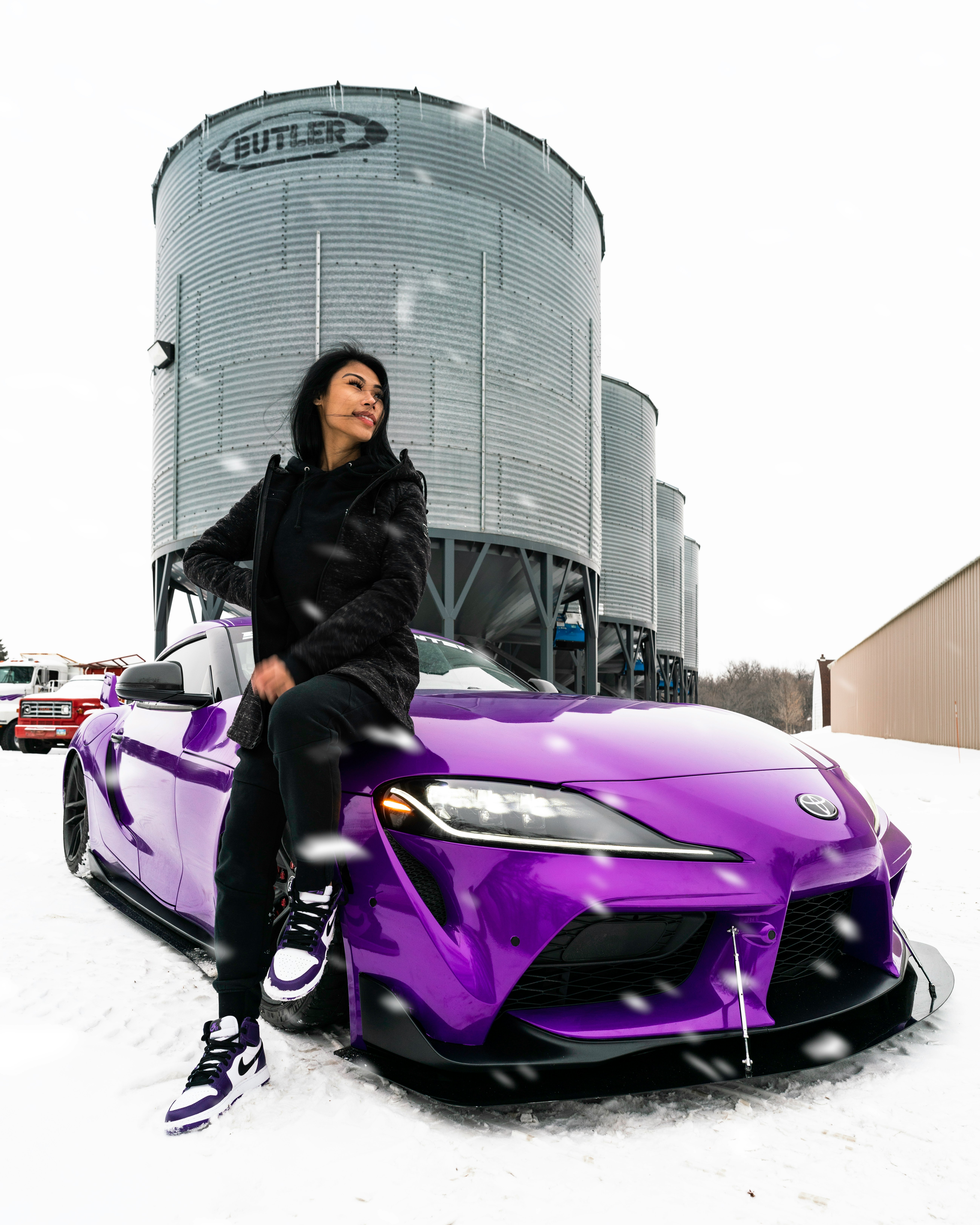 woman in black jacket sitting on purple car